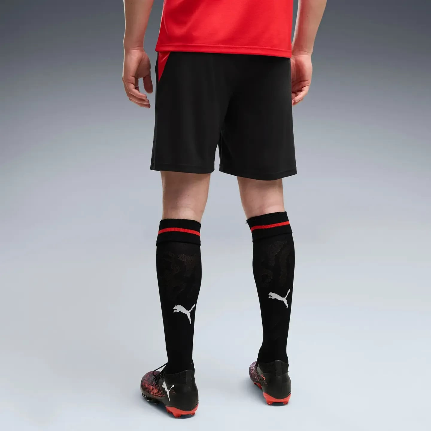 Vue arrière du mannequin portant le short réplique SRFC PUMA noir, chaussettes noires et crampons ro