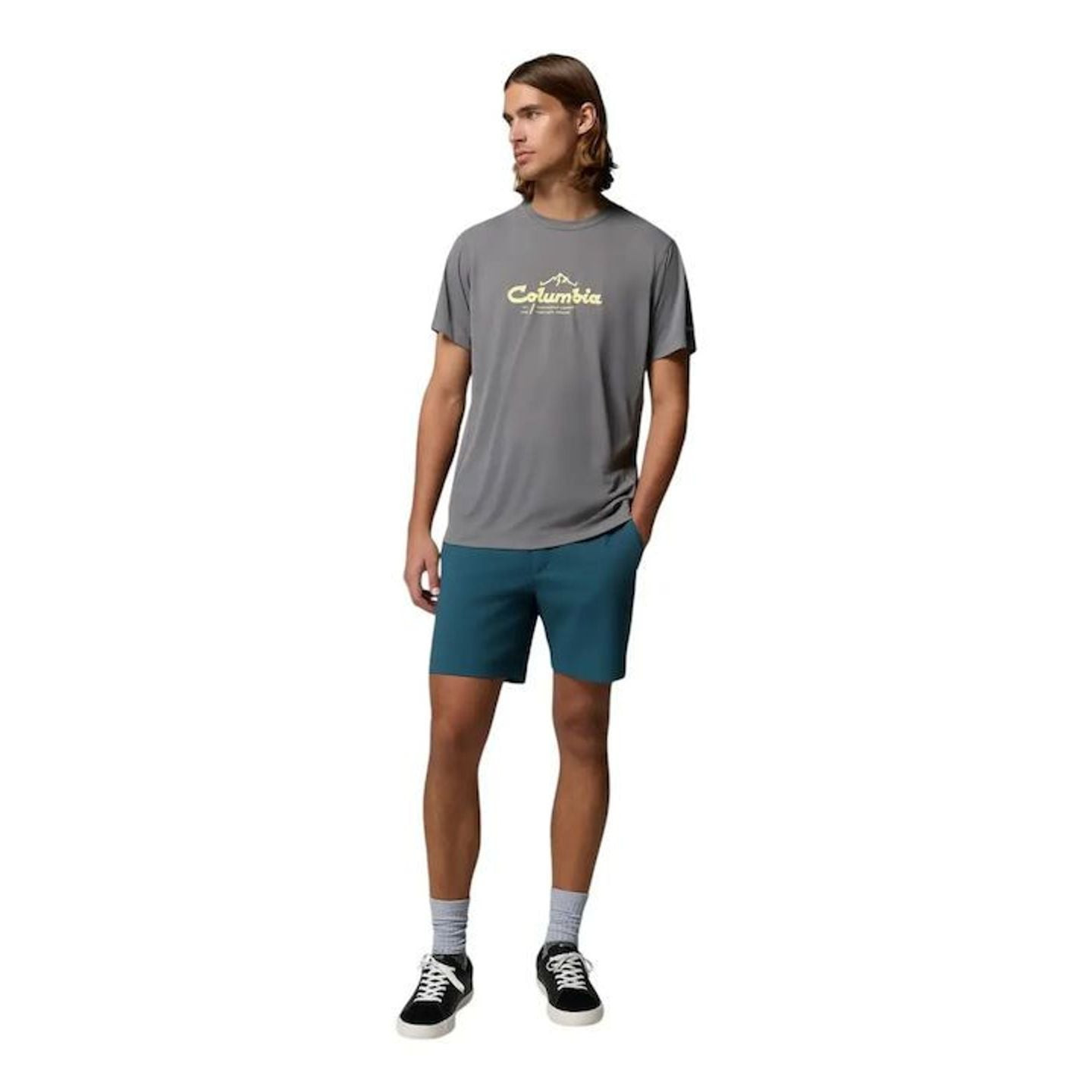 Homme en t-shirt graphique Columbia gris, short bleu canard et baskets, en pied, style extérieur
