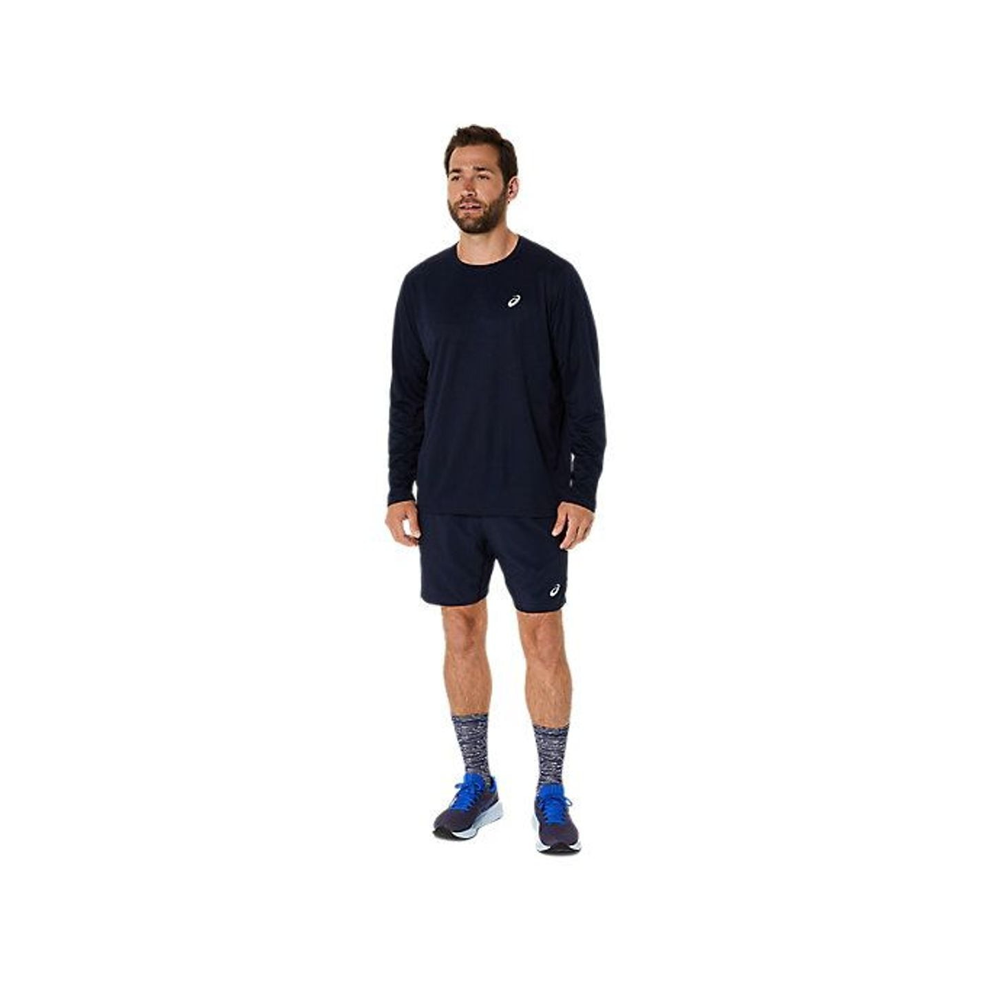 Vue en pied d'un coureur portant l'ASICS Core LS Top, short bleu marine, chaussettes à motifs et cha