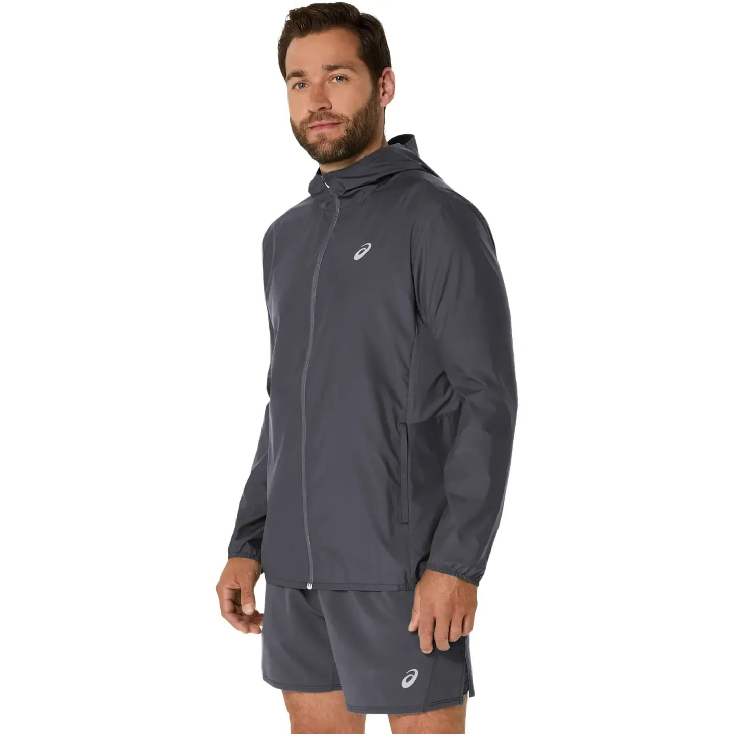 Homme portant la veste de running Asics Core à capuche, coupe-vent déperlante, lors d'un footing urb